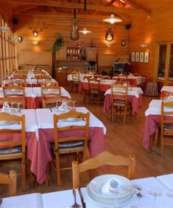 埃斯波特鲁瓦亚酒店的用餐室配有桌椅以及白色和粉红色的桌子