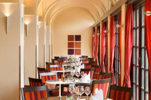 巴特瑙海姆Dolce by Wyndham Bad Nauheim的一间配备有桌椅和红色窗帘的用餐室