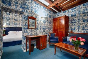巴黎驿站酒店的卧室配有蓝色和白色的壁纸、一张床和一张书桌