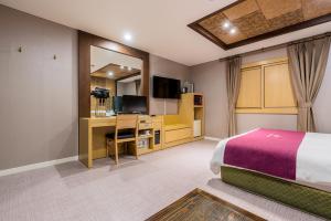 水原市Symphony Hotel的一间卧室配有一张床、一张书桌和一台电视