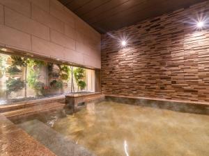别府Super Hotel Beppu Ekimae的一座带石墙的大型室内游泳池