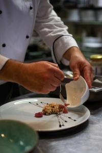 克拉平斯凯托普利采马格达莱纳别墅疗养酒店的厨师正在准备盘子上的菜肴