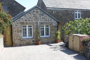 PaulBryher Cottage的石屋设有白色窗户和庭院