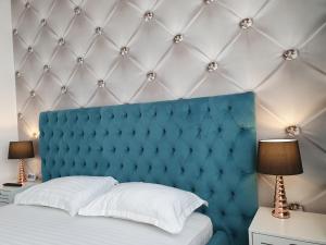 塔古玖ARISTOCRAT CENTRAL的一张带蓝色软垫床头板的床和两盏灯