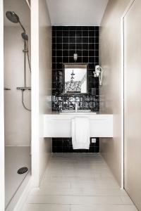 布鲁塞尔La Maison Haute guesthouse的浴室设有白色水槽和黑色瓷砖墙。