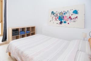 塔拉戈纳LA SURFERA APARTMENT的白色卧室配有一张床,墙上挂着一幅画