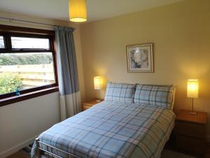 皮特洛赫里Newholme Self-Catering Bungalow的一间卧室配有一张床、一个窗口和两盏灯。