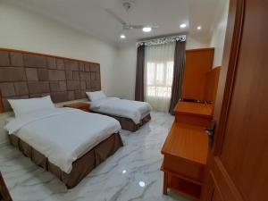 ḨilfAL JOOD HOTEL APARTMENT的酒店客房设有两张床和钢琴