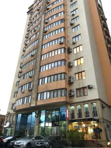 巴库Gallery Lux Hotel Baku的一座高大的建筑,前面有汽车停放