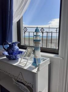 纽卡斯尔Conlyn house的一张桌子、一个灯塔和一个享有海滩美景的窗户