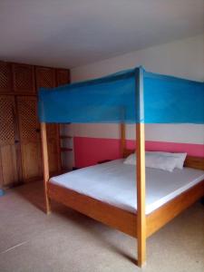 Joal-FadioutAuberge Cœur Océan的一间卧室配有一张蓝色天蓬床