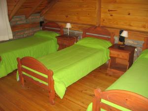 埃斯克尔Cabañas Lorien的一间卧室设有两张绿色的床,铺有木地板