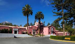 阿雷基帕Wyndham Costa del Sol Arequipa的一条街道前的粉红色房子,种有棕榈树