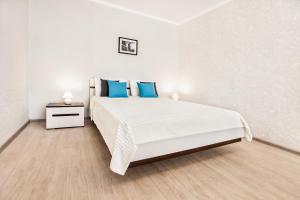 陶里亚蒂Spring Melody Apartment SUTKI LIFE的白色卧室配有一张带蓝色枕头的大床