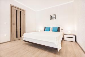 陶里亚蒂Spring Melody Apartment SUTKI LIFE的白色卧室配有一张带蓝色枕头的大床