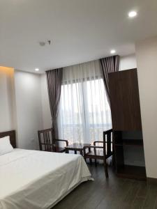 北宁SUN HOTEL & APARTMENT的一间卧室配有一张床、一张桌子和一个窗户。