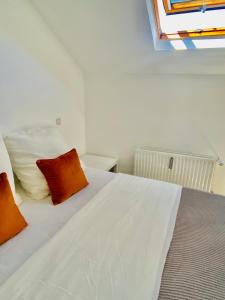 雷米希Cozy flat near Moselle Remich的卧室配有带橙色枕头的白色床