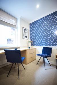 波兹南Apartamenty Klasztorna 25的蓝色瓷砖的房间,有两把椅子和一张桌子