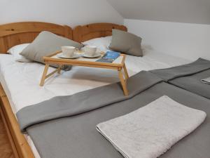 伦达瓦Apartma med vinogradi的一张带托盘的床铺,上面有2个杯子和一张桌子
