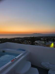 费拉Eternity Suites Santorini的浴缸位于阳台顶部,享有日落美景