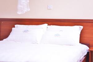 KalisizoNabisere Hotel Kalisizo的一张带白色床单和枕头的床