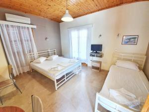 雷夫卡达镇Alexaria Holidays Apartments的客房设有两张床、一张桌子和电视。