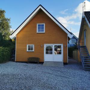 TranebjergSamsø værelseudlejning的一间棕色的房子,有白色的门和楼梯