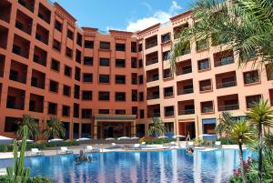 马拉喀什莫加多尔门扎公寓酒店的一座大型建筑,前面设有一个大型游泳池