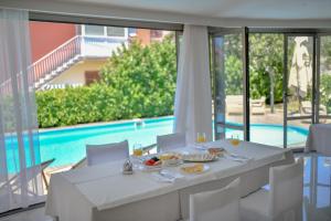 苏科尚Hotel Levant的一张带食物和葡萄酒的白色桌子以及游泳池