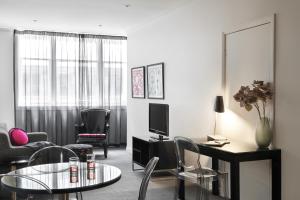 墨尔本普特希尔公寓酒店 - 弗林德斯巷的客厅配有桌椅和电视。