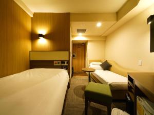 东京池袋站北口乐活超级酒店的酒店客房设有两张床和一张桌子。