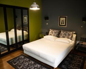 雅典安德洛墨达套房公寓式酒店的卧室配有白色的床和镜子