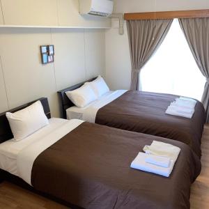 宫古岛Y' RISE TO HOTEL Miyakojima的酒店客房设有两张床和窗户。