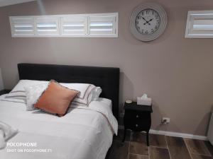 GorokanLa Nest Private Studio的卧室配有一张挂在墙上的带时钟的床