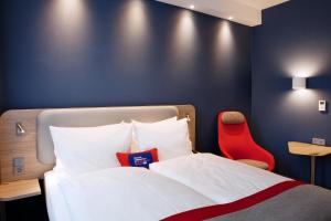 锡根锡根快捷假日酒店的一间卧室配有一张床和一张红色椅子