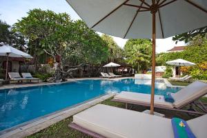 沙努尔纳塔芭利别墅酒店的一个带躺椅和遮阳伞的游泳池