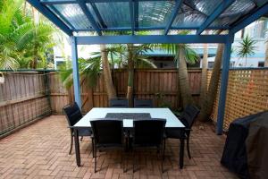 拜伦湾Byron Bay Accom Unit 3 41 Childe Street - Belongil Beach Apartment的棕榈树庭院内的桌椅