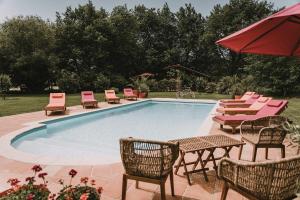 波讷地区圣朱利安Le Domaine de Petiosse的一个带桌椅和遮阳伞的游泳池