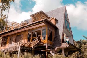 曼巴豪Camiguin Volcano Houses - A-Frame house的两个人站在门廊上的房子