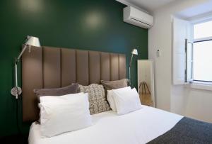 里斯本Flats Castelo - HOrigem的卧室配有一张带白色床单和枕头的大床。