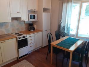 萨翁林纳huoneisto 2的厨房配有白色橱柜和带炉灶的桌子。