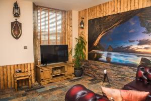 圣奥斯特尔Deluxe Pirate's Cove Themed Apartment的客厅配有电视和墙上的绘画