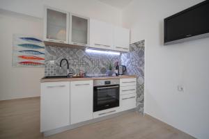 拉巴克Apartment IVA的一间厨房,配有白色橱柜和墙上的电视