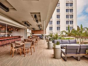 洛杉矶Hotel June West LA, a Member of Design Hotels的酒店庭院设有桌椅和酒吧。