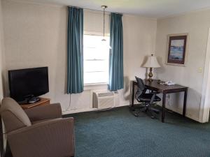 威尔明顿Azalea Inn & Suites的酒店客房设有一张桌子、一把椅子和一个窗户。
