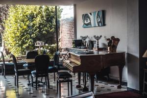 鲁贝La Maison Bleue de Roubaix的一间设有钢琴、桌子和椅子的客房