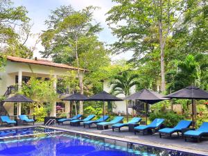 锡吉里亚花卉园生态村酒店的一个带蓝色椅子和遮阳伞的度假游泳池