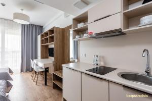 华沙Apartament w Warszawie dedykowany parking podziemny w cenie, WiFi, blisko centrum New apartment in Warsaw finished to a high specification fitted out to a high standard on the 7th floor, WiFi, underground parking price included的一个带水槽的厨房和一张书桌