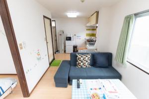 松户市松戸 テイクファイブ 1DK Nomad松戸宿056的一间带蓝色沙发的客厅和一间厨房