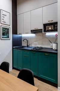 利沃夫Emerald Lux Apartment. LiveInLviv的厨房配有绿色橱柜和木桌